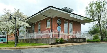 Historic brick train depot building with white trim and railing.