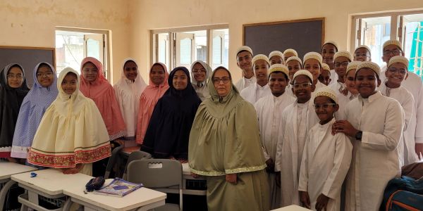 Group of students and a teacher in traditional attire in a classroom.