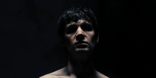 Dimly lit portrait of a young man in shadows.