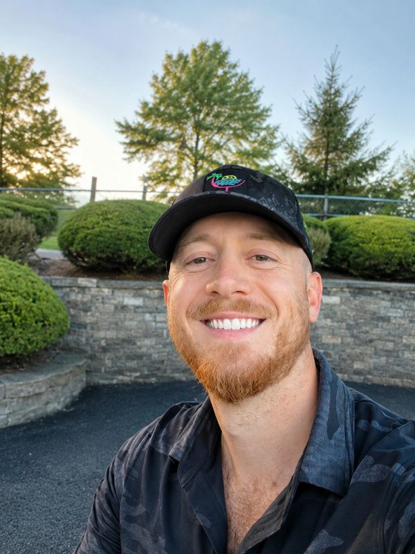 Man in a black cap smiling outdoors.