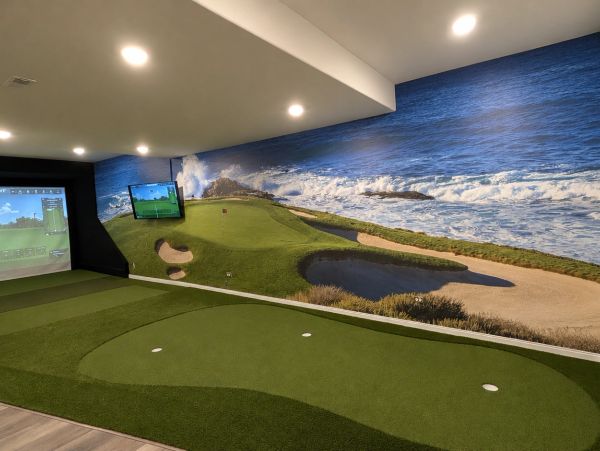 Indoor golf simulator with ocean mural.