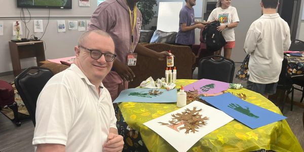 People engaged in a craft activity with colorful paper and glue at a table.