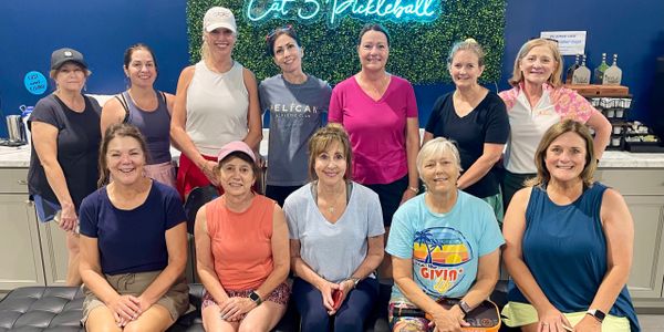 Group of women posing indoors at a pickleball facility.