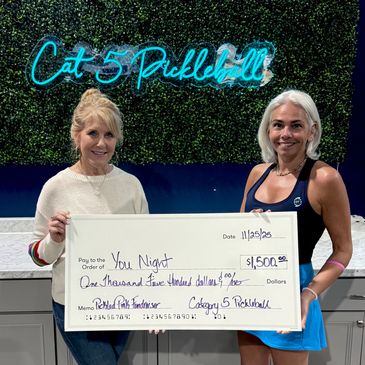 Two women holding a large $1,500 check for a pickleball tournament win.
