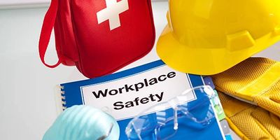 Workplace safety gear including helmet, gloves, mask, and first aid kit.