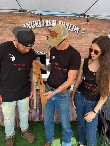 Three people wearing black shirts and jeans, looking at a brown object.