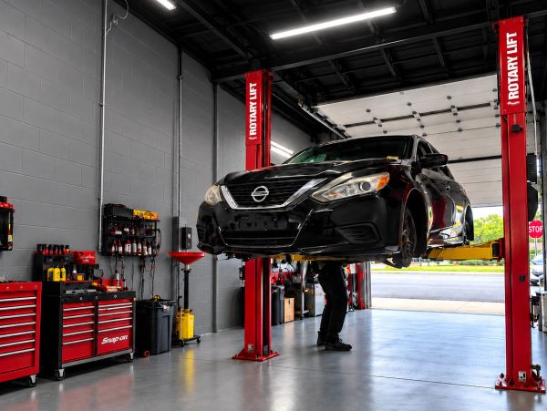 Black Nissan car lifted in a garage for repair.