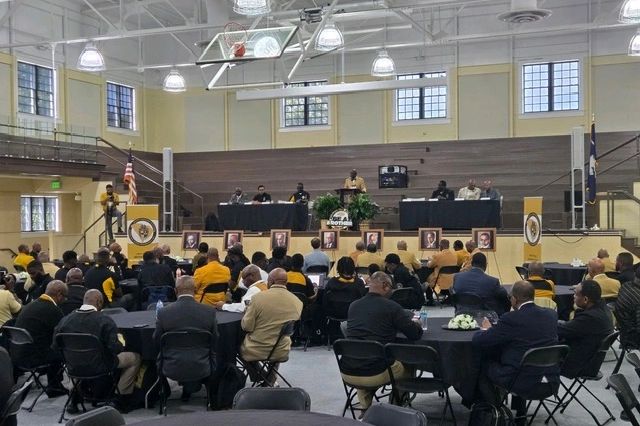 A formal event with a speaker addressing an audience in a gymnasium.