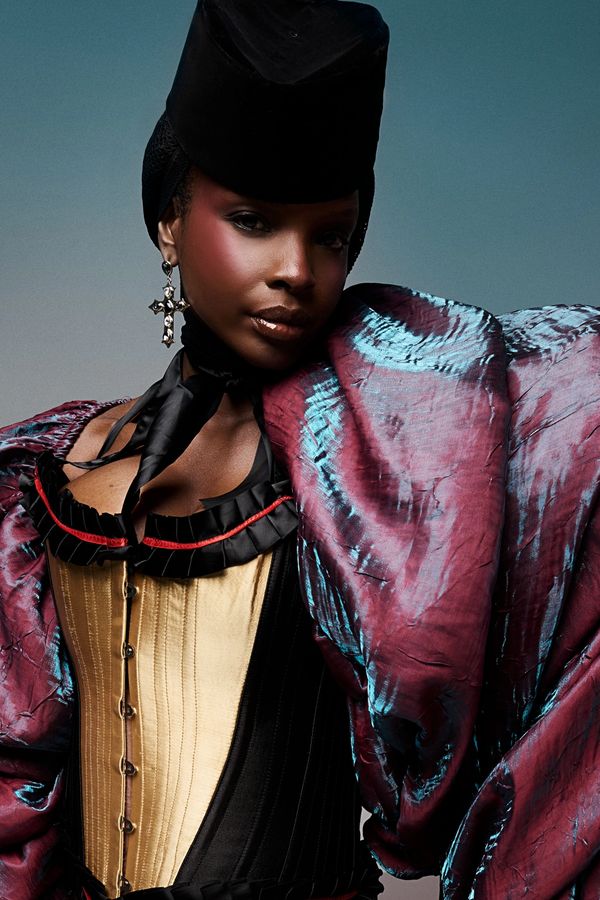 Chic fashion model in flowing dress and statement gold jewelry