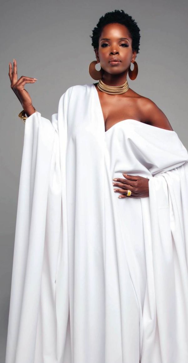 Fashion model posing in a flowing evening gown with gold jewelry