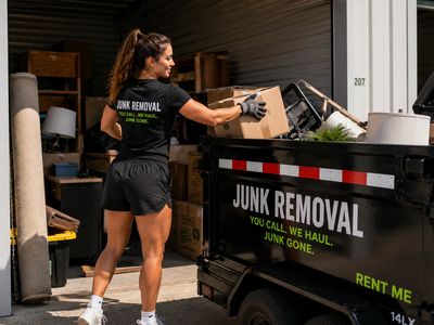 Woman loading a junk removal trailer with boxes and items.