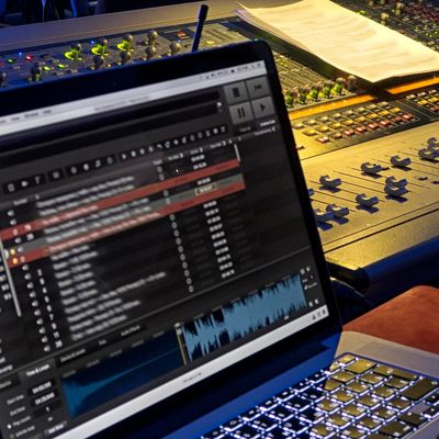 Audiovisual production desk with sound consoles, mixing, and laptops.