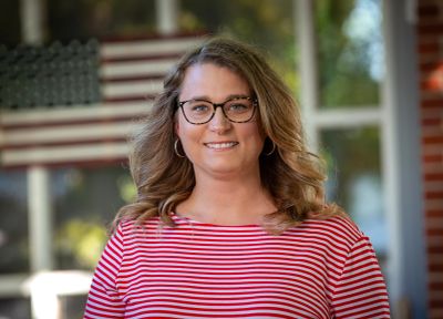 Smiling woman with glasses and striped shirt.