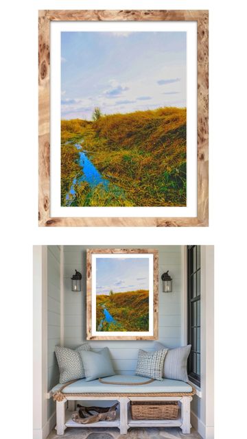 Framed landscape photo with a small stream and golden grass hung over a cozy bench.