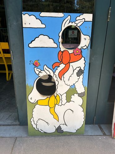 Cartoon llama photo stand-in with cut-out faces.