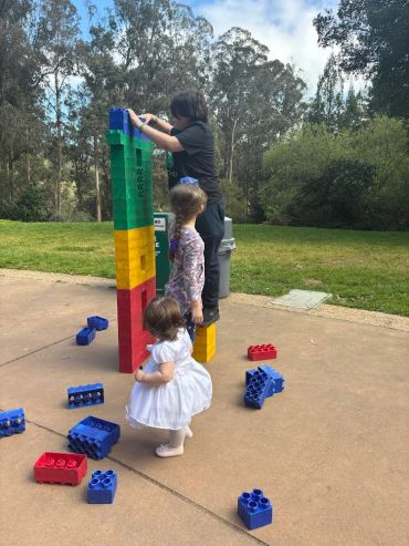 Children building tower with large colorful blocks outdoors.