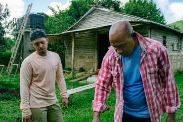 Dos hombres trabajan cerca de una cabaña.