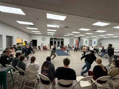 Group of people playing a circle game indoors.
