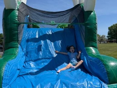 Child sliding down inflatable slide outdoors.