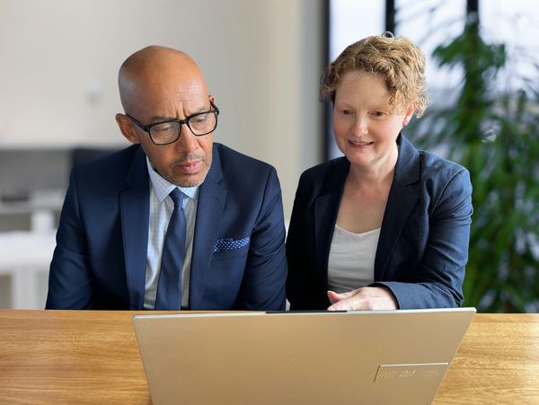 The 2 company directors meeting and looking at a laptop in the office