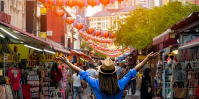 Traditional street in Singapore with lanterns hanging and a woman at the front with open arms