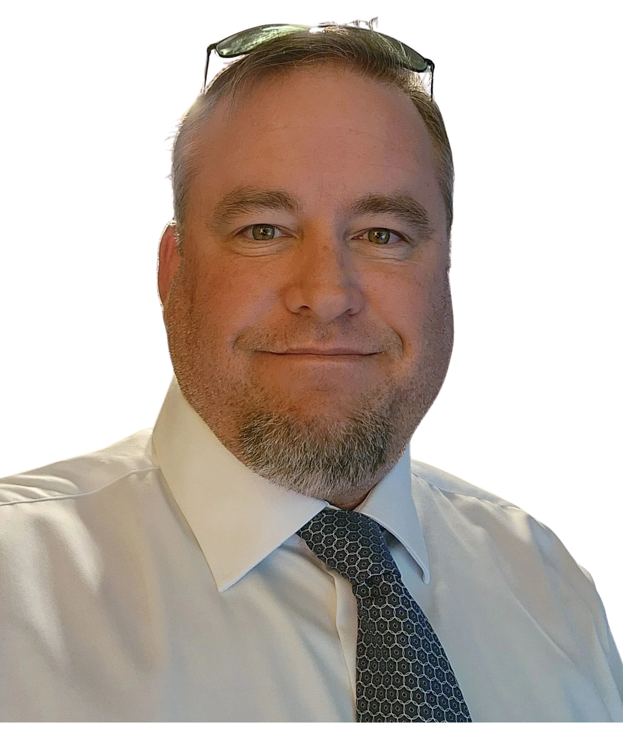 Smiling man in white shirt and patterned tie with glasses on head.