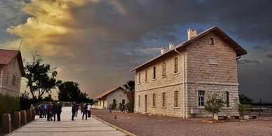Historic stone buildings under a dramatic sunset sky with people walking nearby.