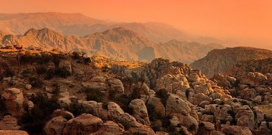 Sunset over rugged mountain terrain with rocky formations.