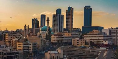 City skyline with modern skyscrapers and a mosque at sunset.