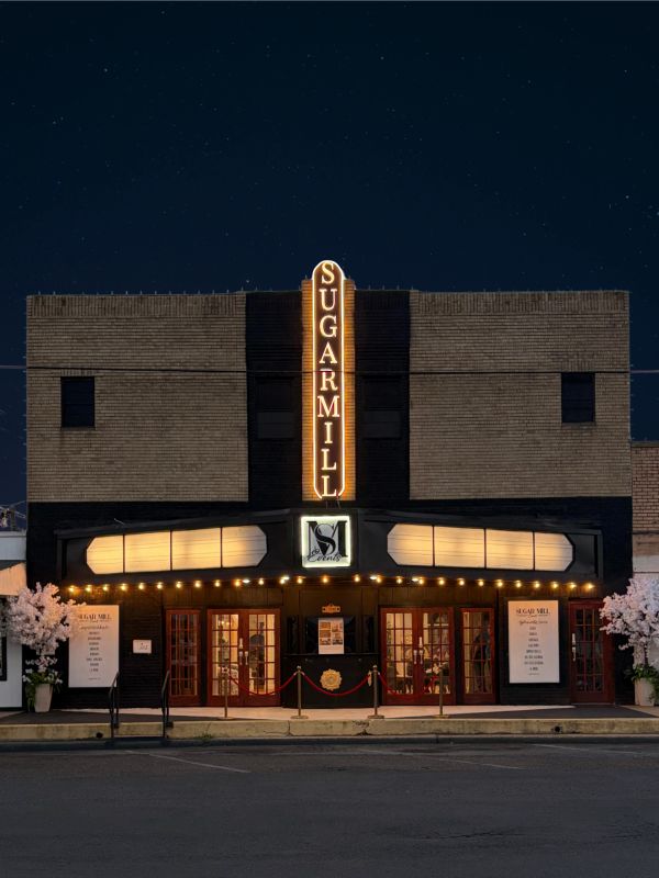 Night view of the Sugarmill theater with illuminated sign and entrance.
