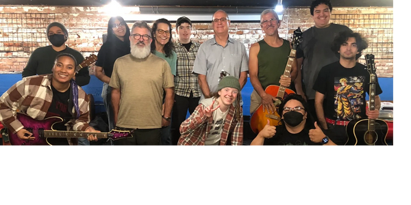 A diverse group of people posing with guitars in a cozy indoor setting.