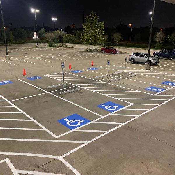 Empty parking lot with multiple handicap spots at night.