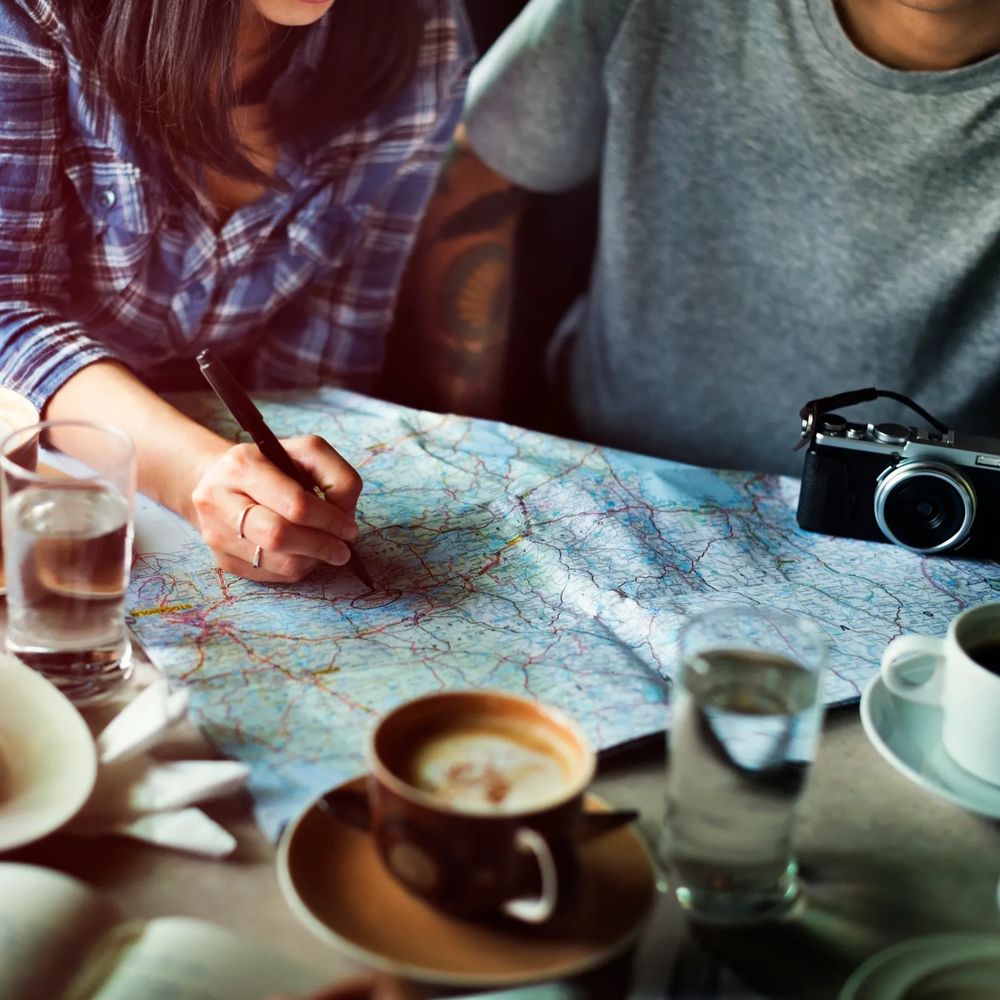 Two people planning a trip with a map, coffee, and a camera.