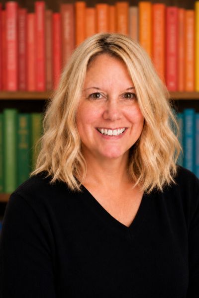 Smiling woman with blonde hair in front of colorful books.