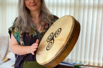 Woman playing a hand drum with a spiral design.