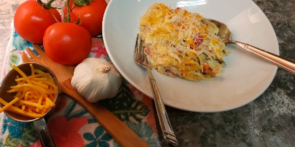 Plate of cheesy baked pasta with tomatoes and garlic.