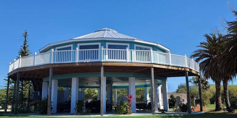 Elevated round house with white railing on a sunny day.