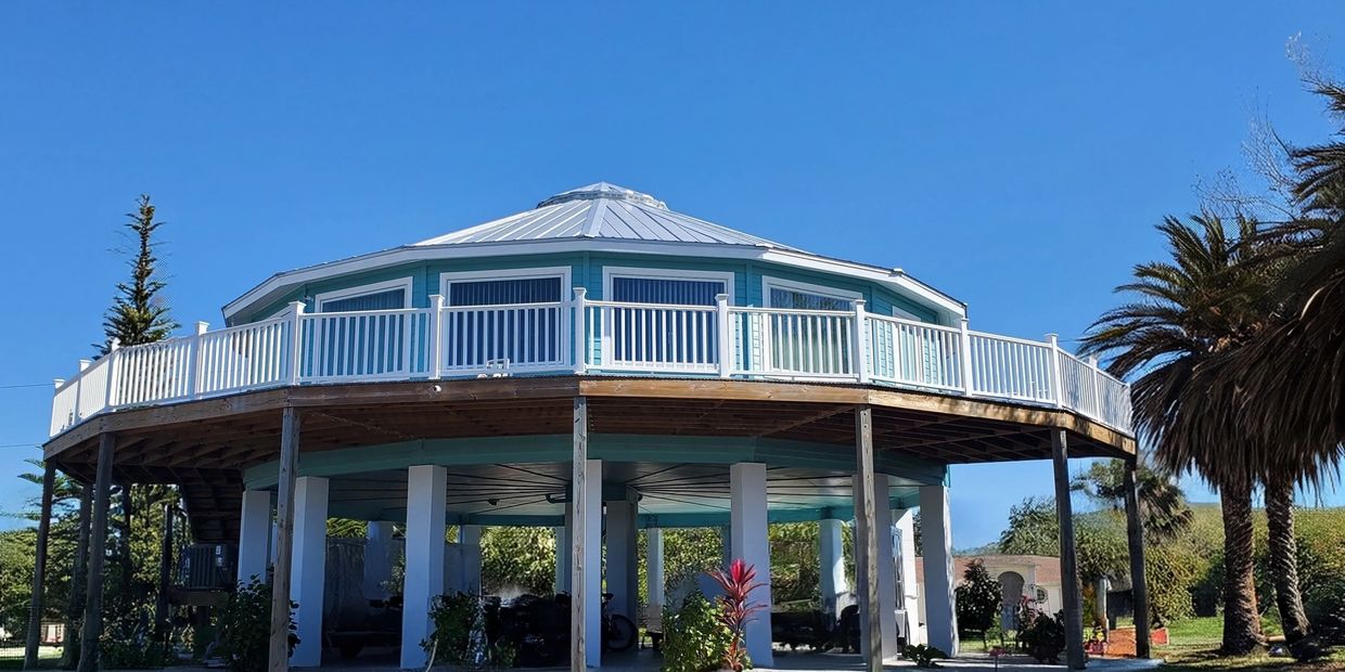 A unique octagonal house elevated on stilts with a blue sky background.