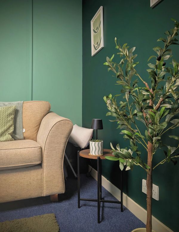 Cozy room corner with beige couch and green decor.