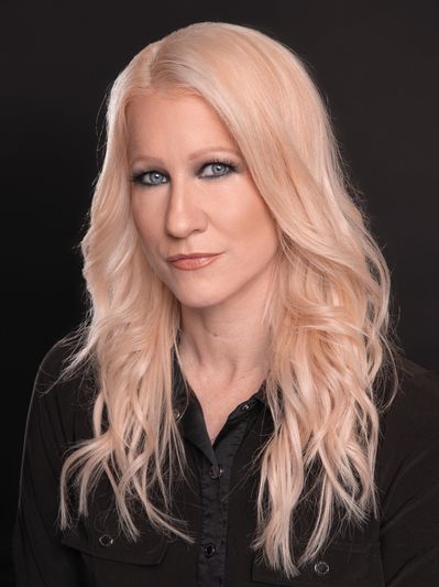 Blonde woman with wavy hair posing against a black background.