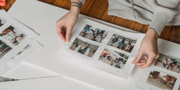 Person organizing printed photos on table.