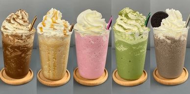 Five colorful milkshakes with whipped cream and toppings.