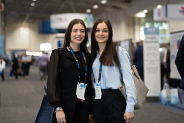 Two young women smiling at a conference with badges and lanyards.