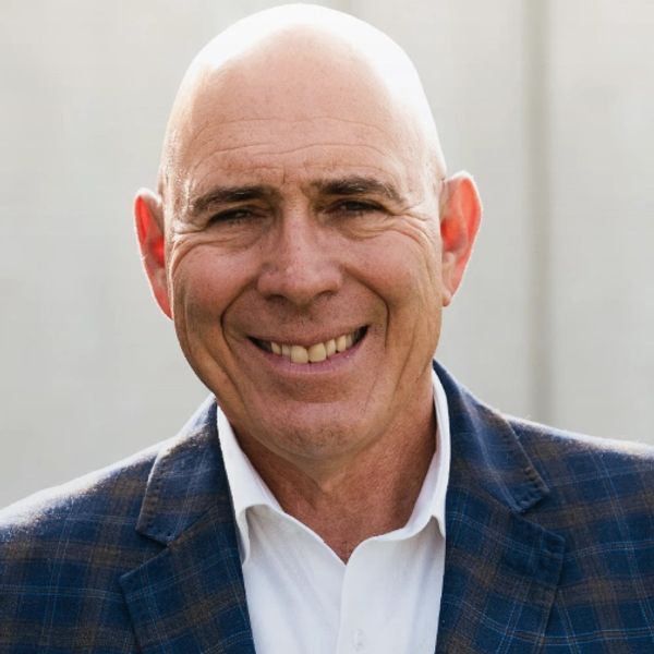 Smiling bald man in a checked blazer and white shirt.