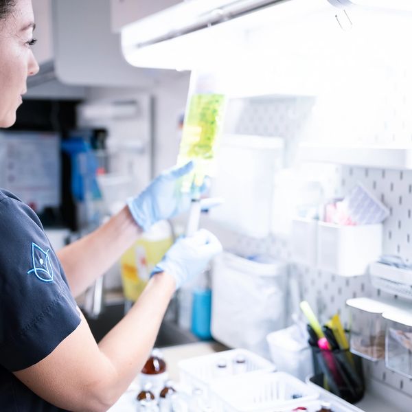 Person examining a medical fluid bag in a clinical setting.