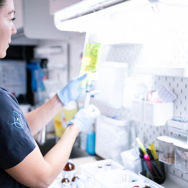 Person examining a medical fluid bag in a clinical setting.