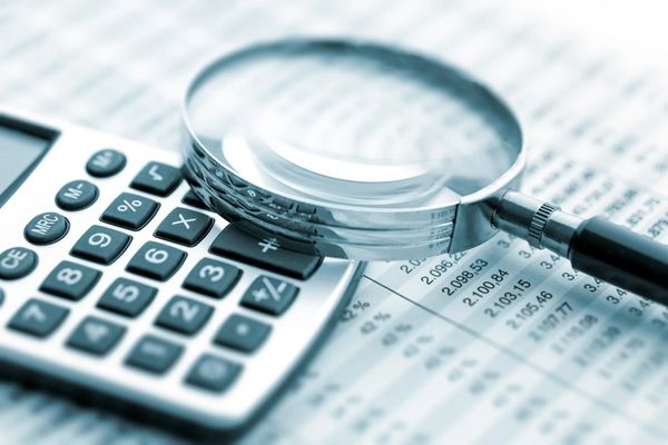 Magnifying glass on calculator and financial document.