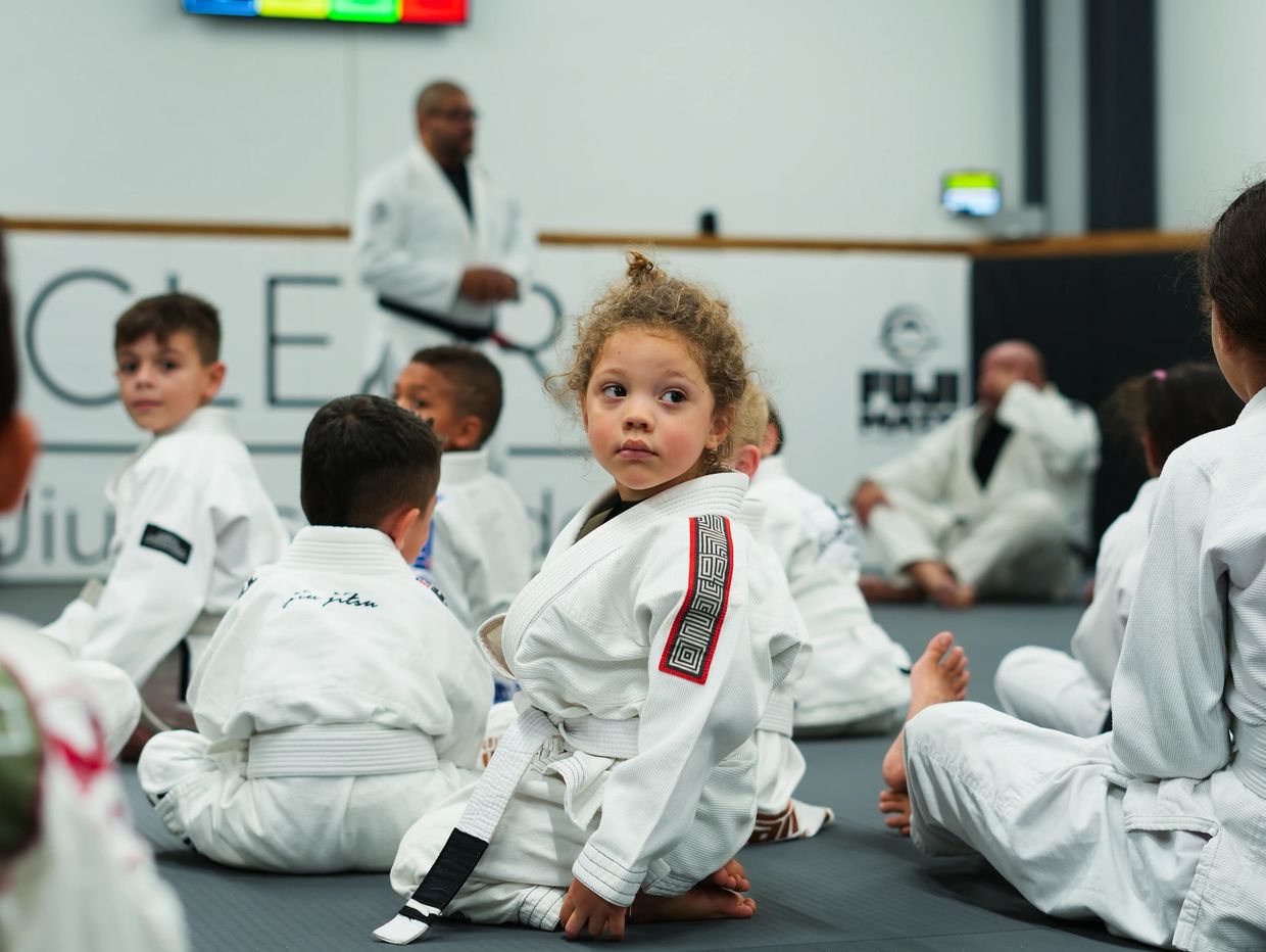 Children learning Brazilian Jiu-Jitsu in a dojo.