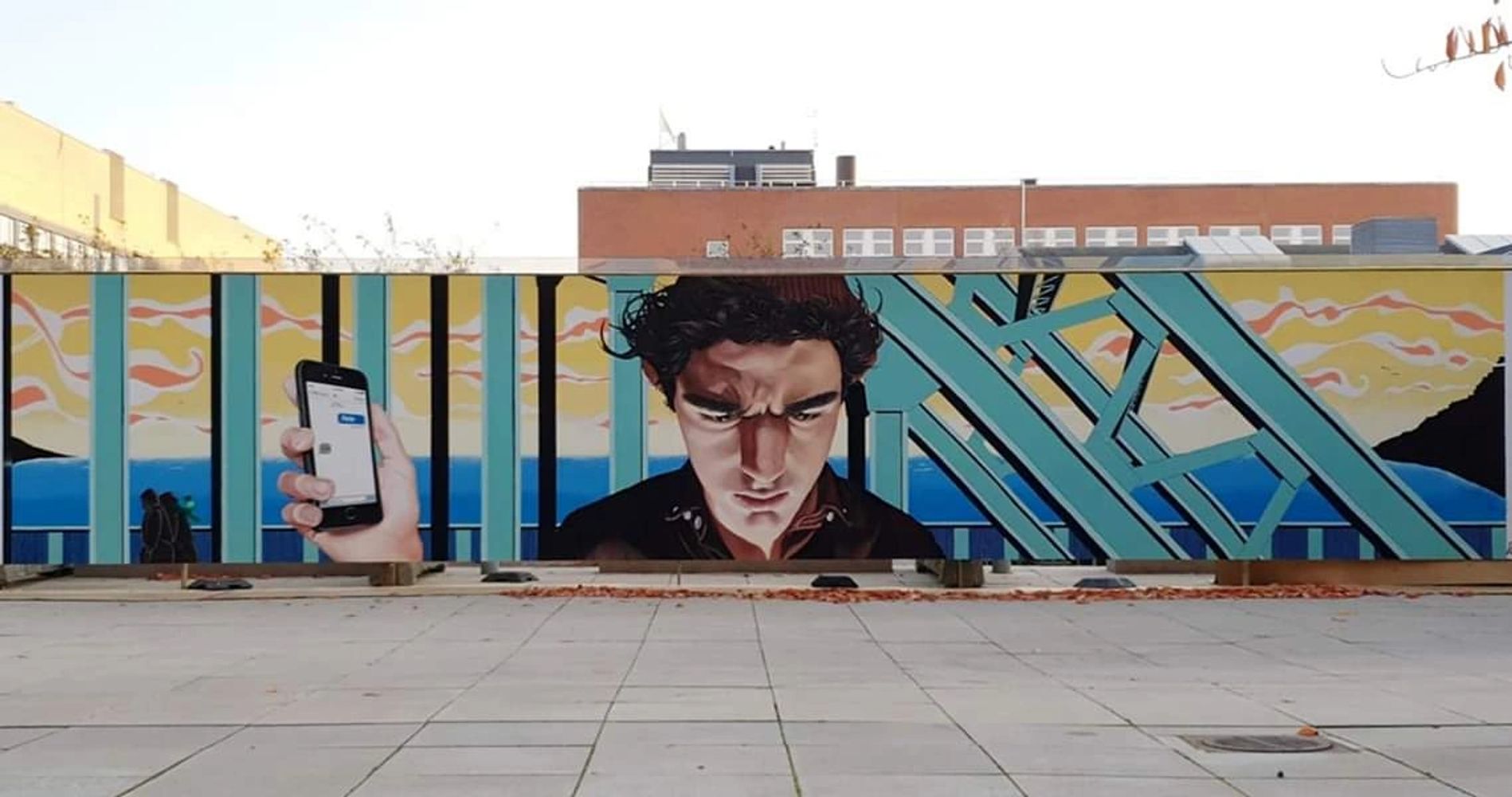 Ikke Lydeking mural of man standing on bridge holding a phone in his hand. The mural is at Lundbeck