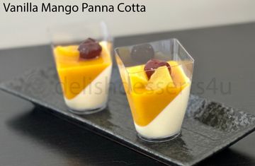 Two vanilla mango panna cotta desserts in clear cups on a black tray.